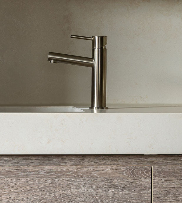 Close up of an Arli Homes bathroom tap and vanity witha sleek modern tap in brushed nickel and a thick stone benchtop